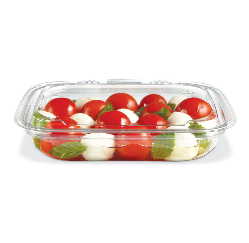 Caprese salad with cherry tomatoes, mozzarella balls, and basil in a clear plastic container
