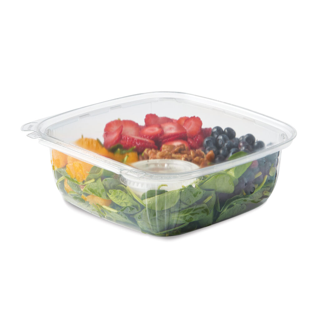 Salad in a clear container with leafy greens, strawberries, blueberries, oranges, and nuts