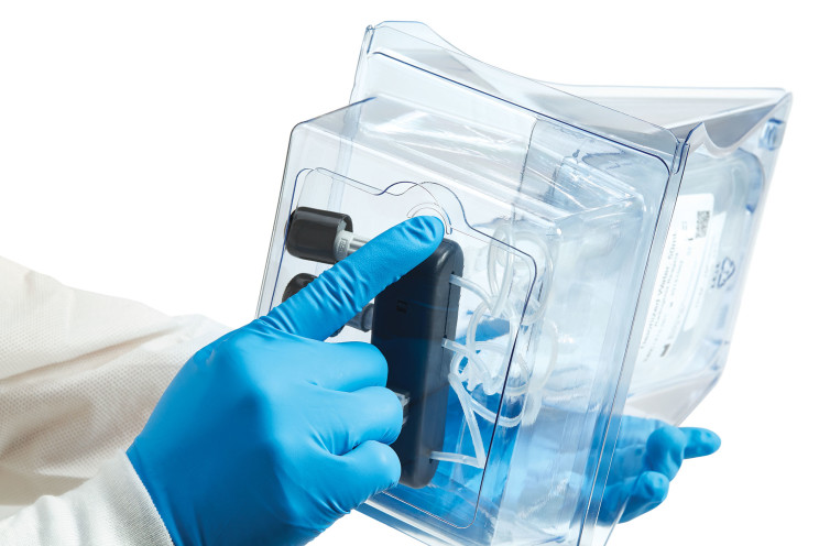 Gloved hand pointing to a component inside a clear medical device housing