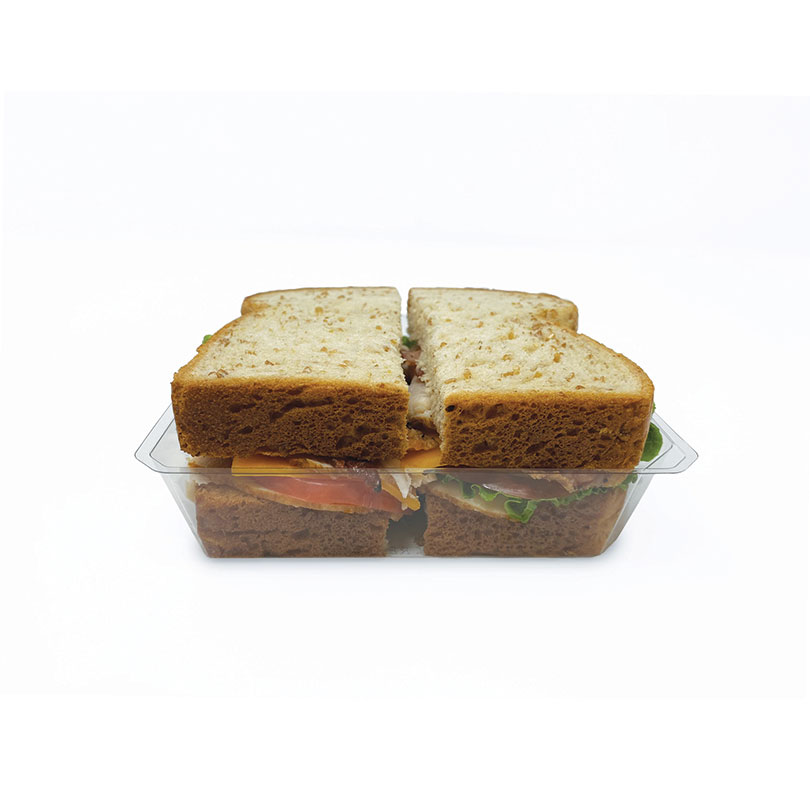Two sandwiches cut into halves with lettuce, tomato, and cheese in a clear container