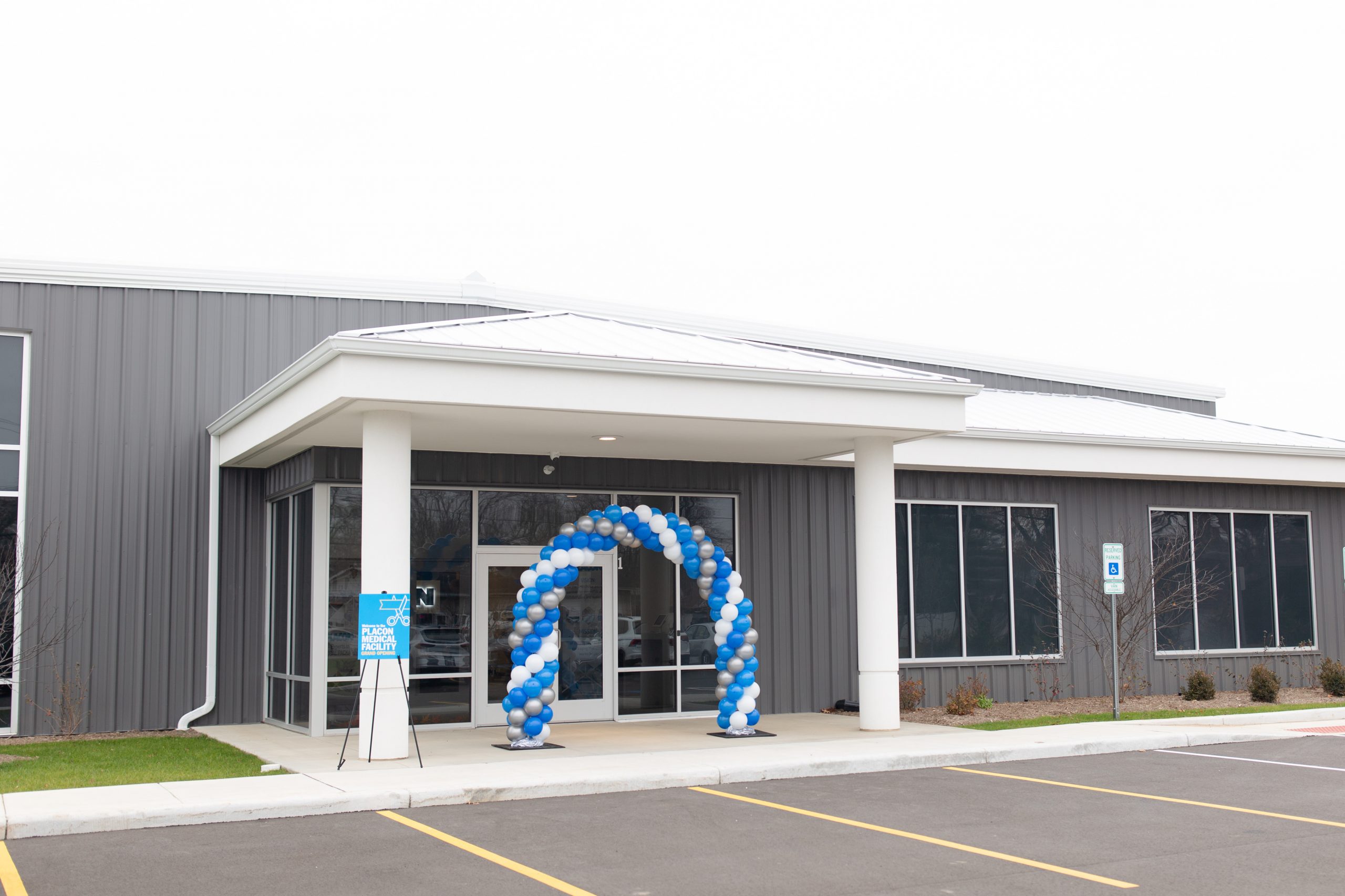 Medical facility entrance decorated with a blue, white, and silver balloon arch for its grand opening