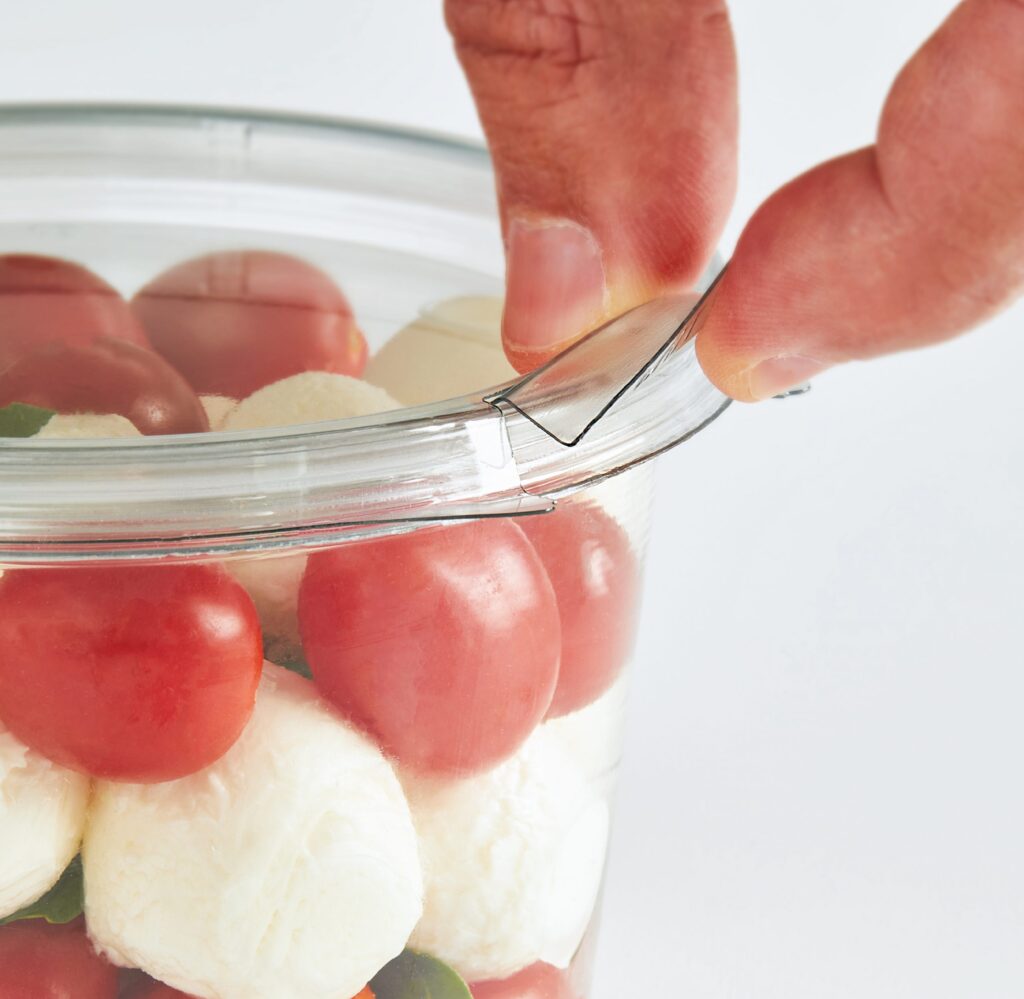 Hand using tweezers to arrange tomatoes and mozzarella on a plate