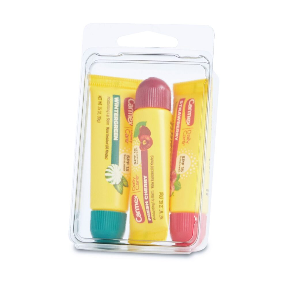 Three Carmex lip balm tubes in a clear package with teal, yellow, and red caps