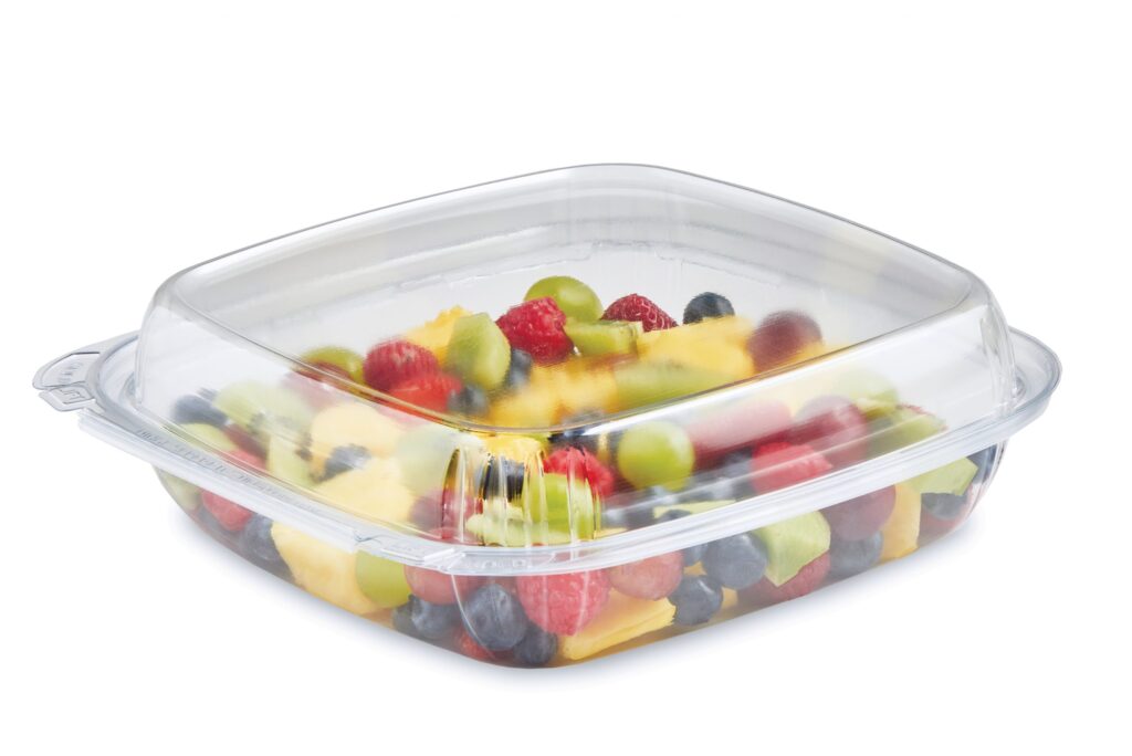 Clear rectangular container filled with mixed fruit, including berries, grapes, kiwi, pineapple, and melon