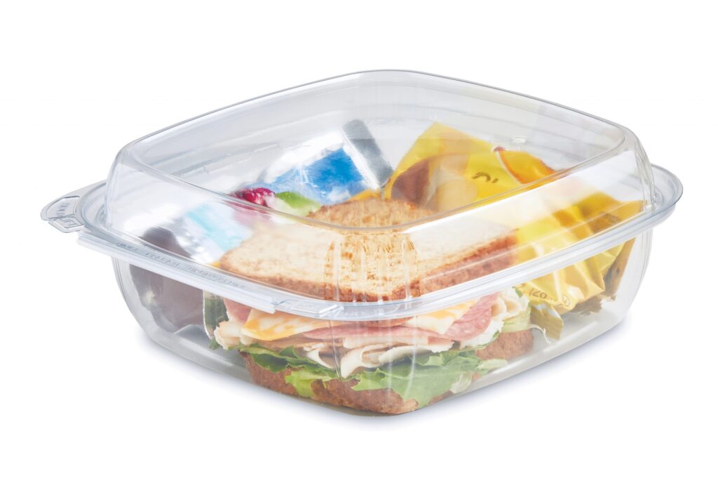 Clear plastic food storage container holding a sandwich and assorted fruit