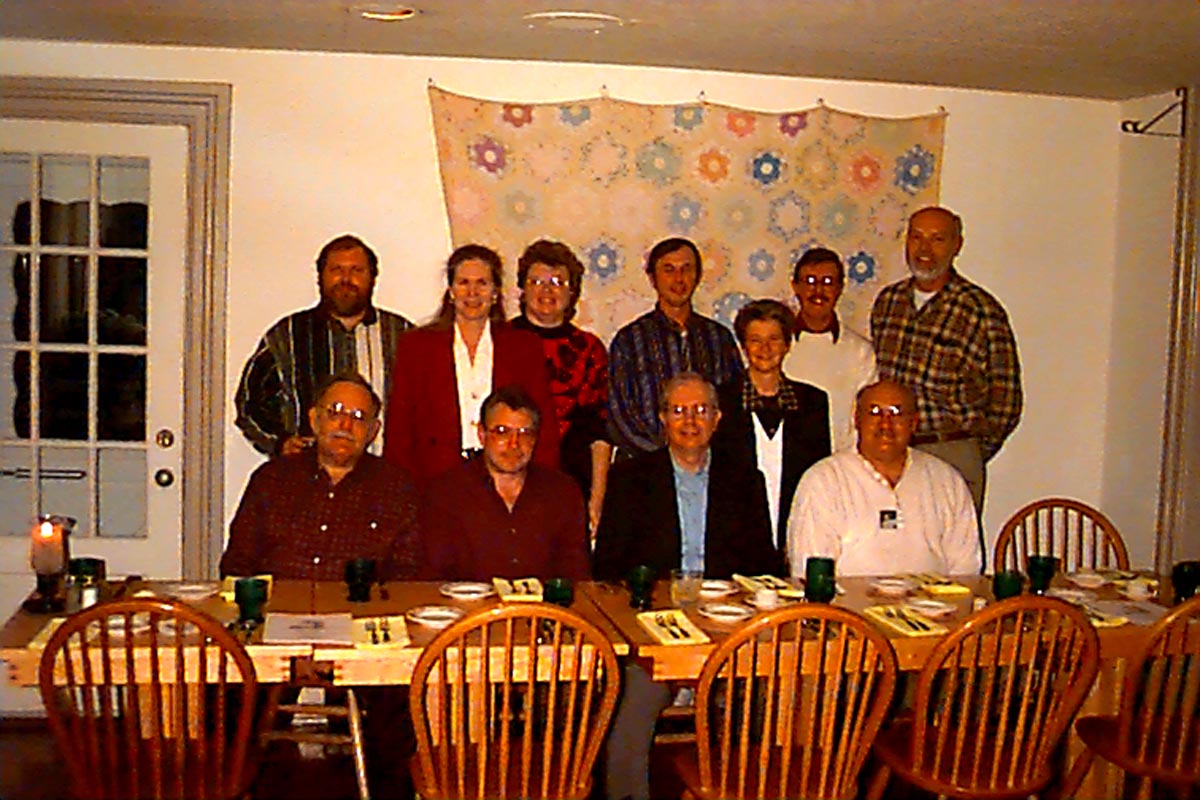 Careers 3 Group of 11 people posing behind a set dining table in a home