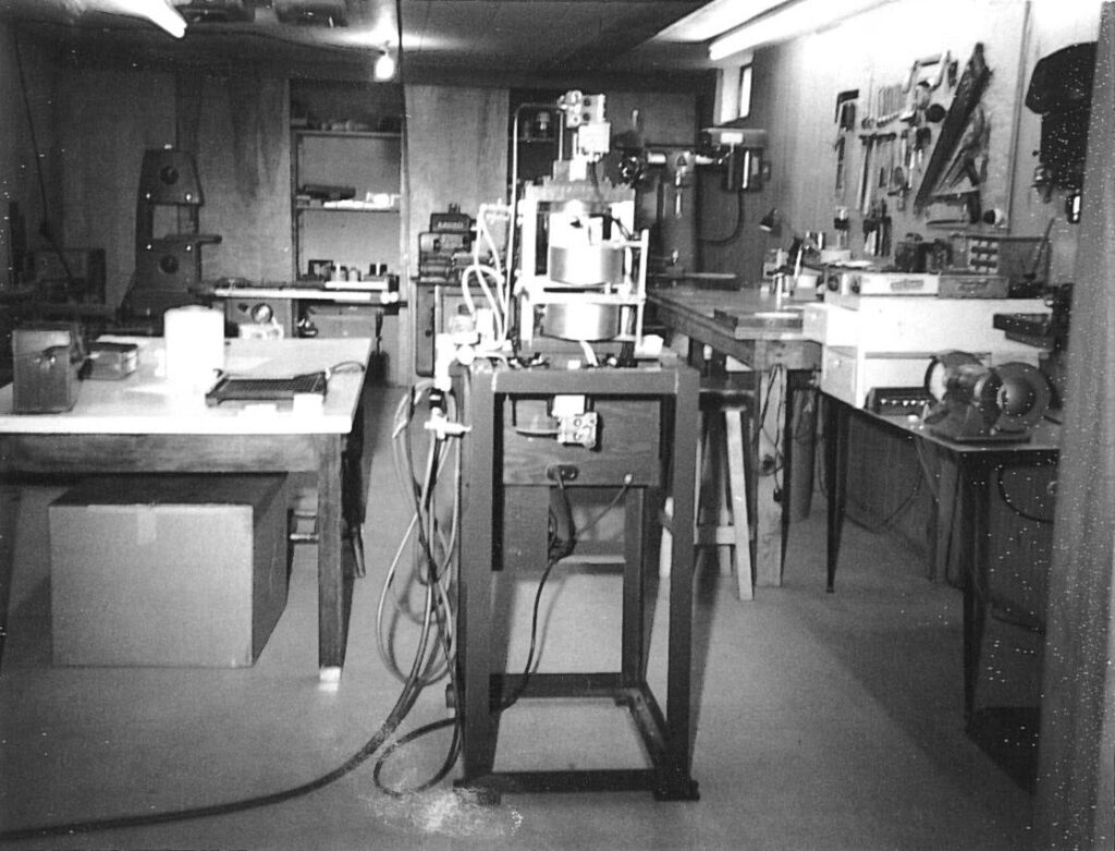 A vintage workshop filled with machinery, tools, workbenches, and equipment