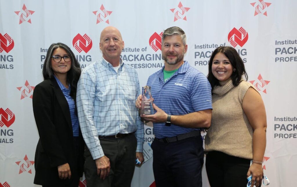 Four people pose together as a man holds a winner’s award at an Institute of Packaging Professionals event