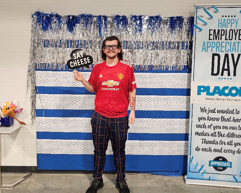 Careers 33 Person in a Manchester United jersey holds a “SAY CHEESE” sign at an employee appreciation event