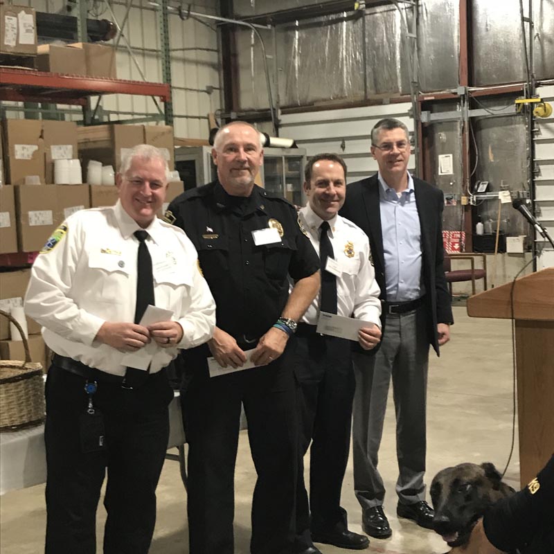 Careers 30 Four men, including three in uniform, pose together in a warehouse beside a podium and a service dog