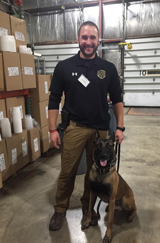 Careers 27 Police officer standing with a leashed Belgian Malinois in a warehouse
