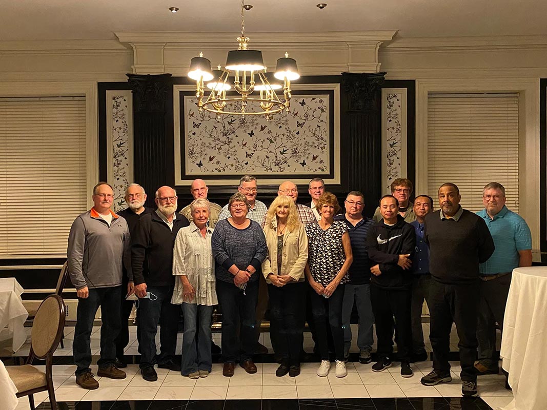 Careers 21 Group portrait of 16 adults standing indoors beneath a chandelier