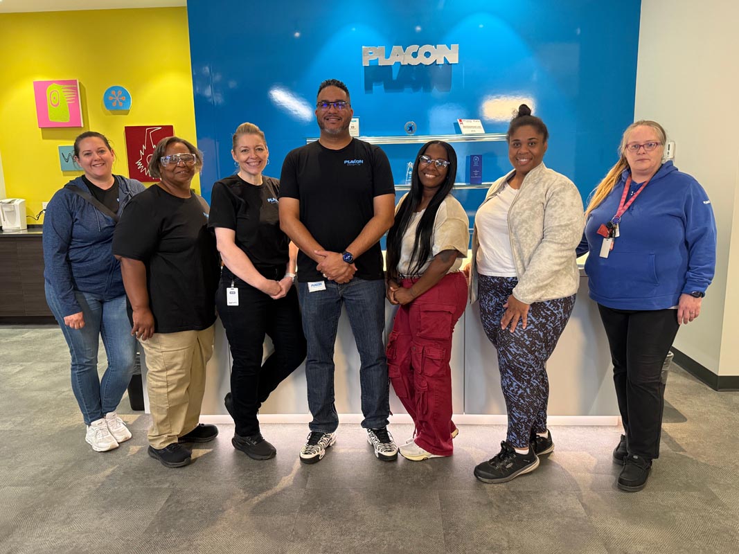 Careers 19 Seven people pose together in front of a reception desk beneath a PLACON sign