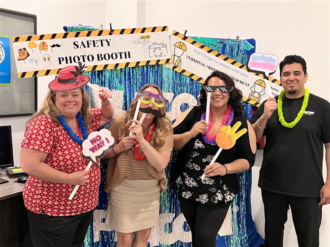 Careers 18 Four adults pose with photo booth props beneath a “Safety Photo Booth” sign and safety-themed decorations