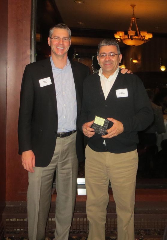 Careers 16 Two men wearing name badges pose together indoors; one holds a small award