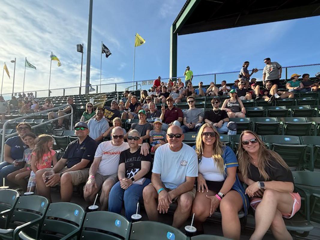 Careers 8 Spectators pose for a group photo in outdoor stadium bleachers beneath several flags