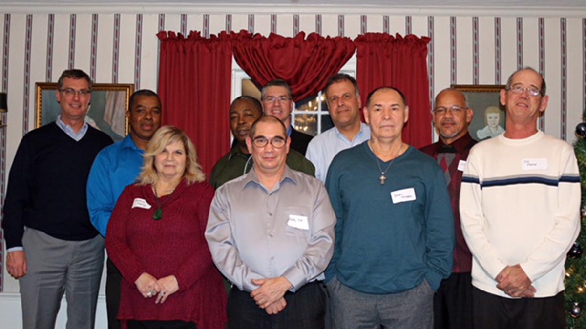 Careers 4 Ten adults posing together indoors in front of red curtains