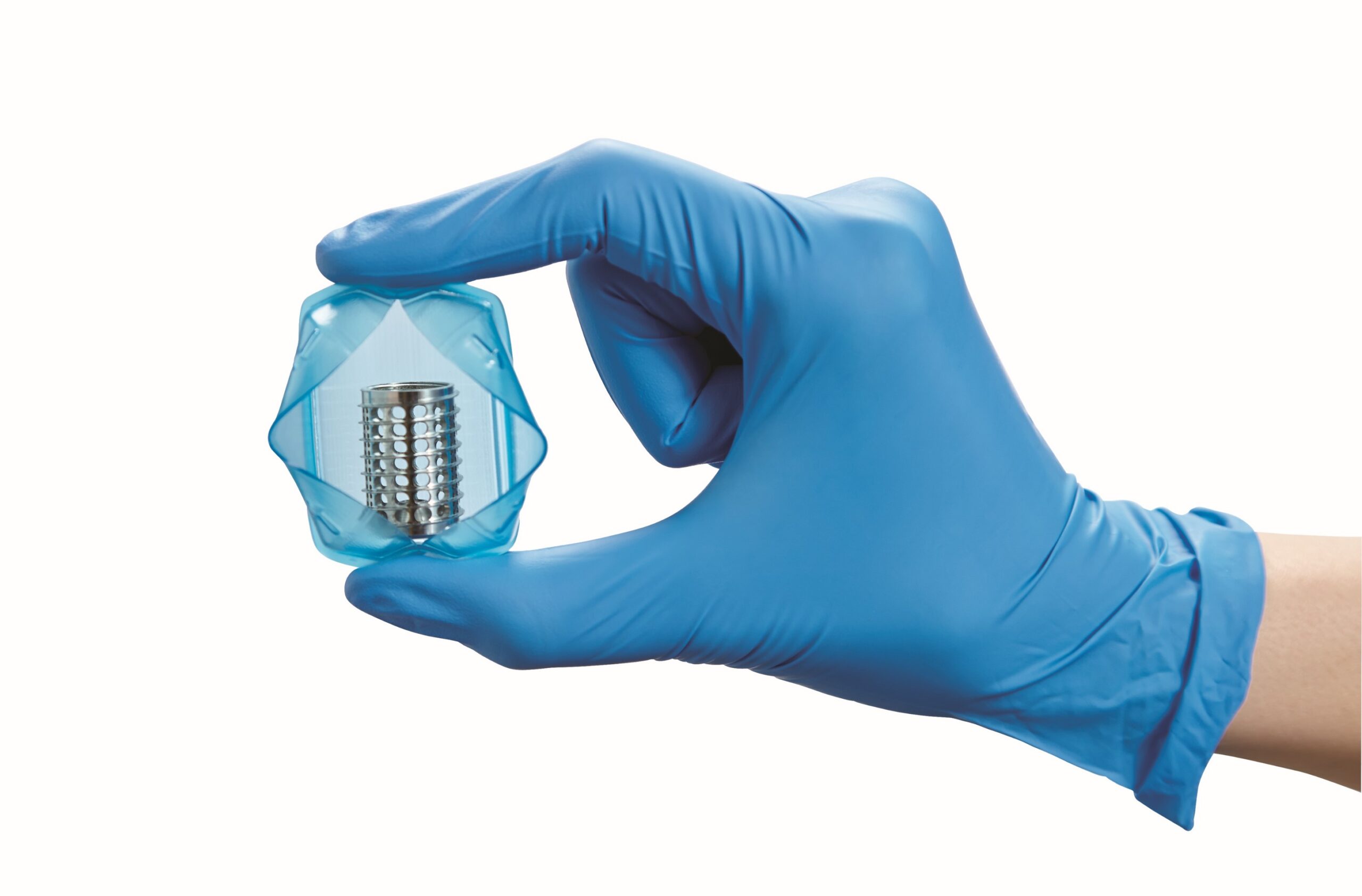 Gloved hands hold a clear container with a metal instrument inside
