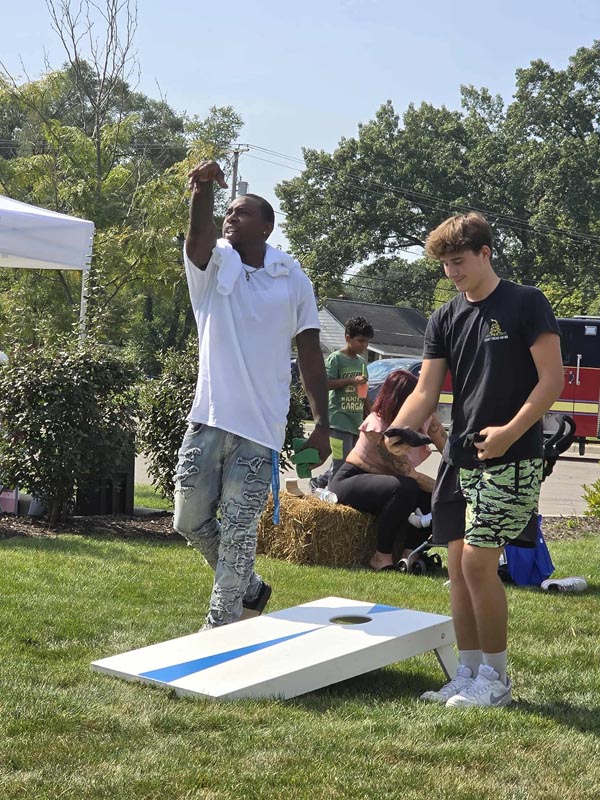 Careers 28 A man tosses a beanbag toward a cornhole board while another player watches at an outdoor event
