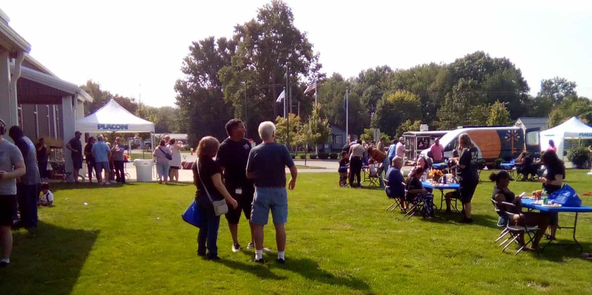 Careers 24 People gather outdoors at a community event with tents, food tables, and a vendor trailer