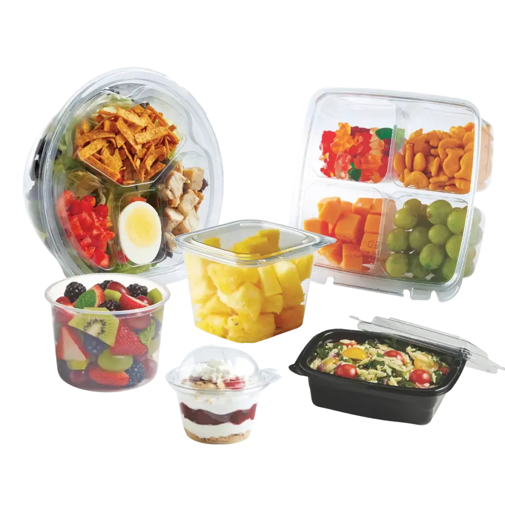 Assortment of prepared meals and snacks in clear containers, including fruit, vegetables, chicken, crackers, pasta salad, and dessert
